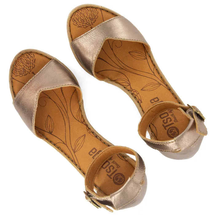 Pair of gold sandals with embossed design on a white background