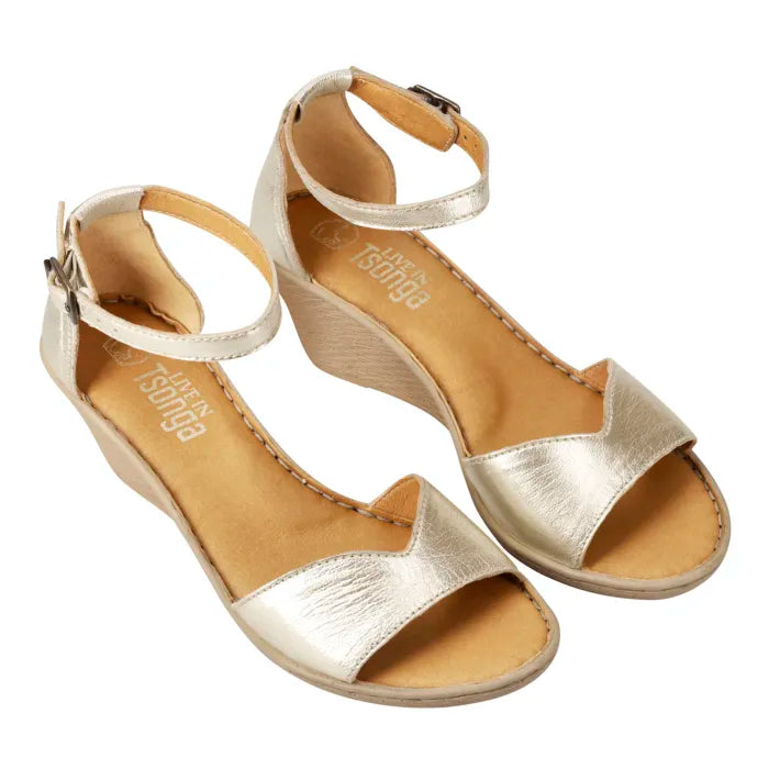 A pair of metallic gold wedge sandals with ankle straps and open toes, shown on a plain white background.