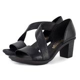 Black heeled sandals with criss-cross straps on a white background