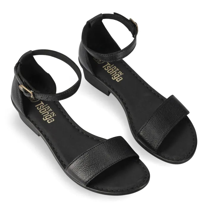 A pair of black low heeled sandals with ankle straps shown on a white background. The brand name 'Tsonga' is printed in gold on the inner sole.