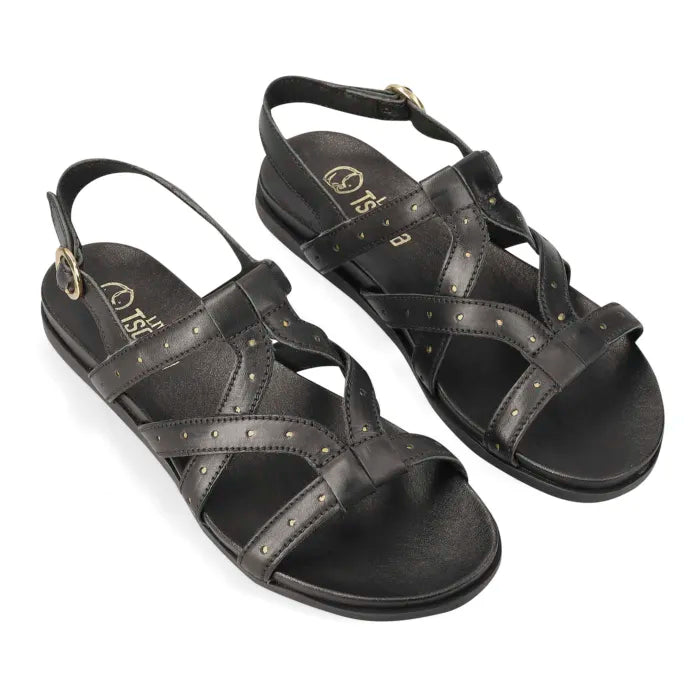 A black leather flat sandal with multiple crisscross straps adorned with small metallic holes, an adjustable ankle strap, and a gold-tone buckle, shown against a plain white background.