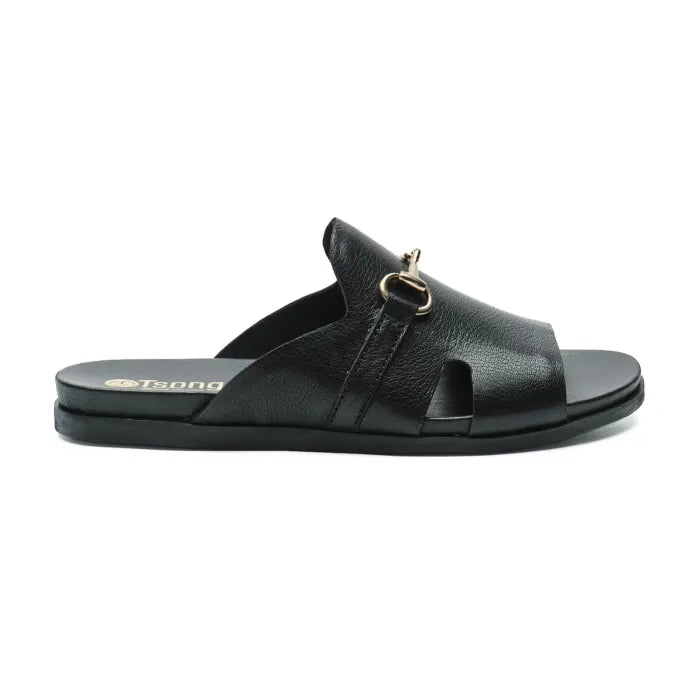 A single black leather slide sandal with a gold-tone horsebit detail on the strap, shown in a side profile against a white background. The brand name 'Tsonga' is visible in gold lettering on the heel of the footbed.