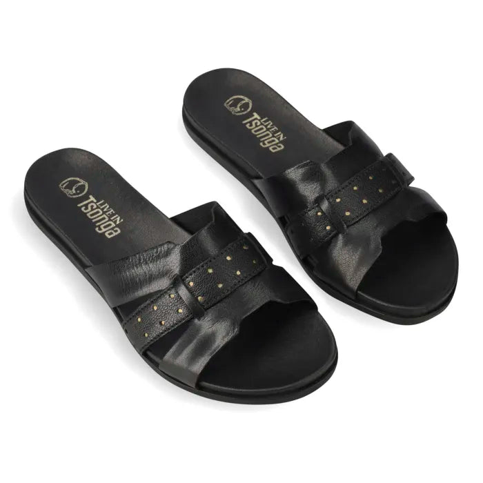 A pair of black slide sandals with double straps and small gold-tone holes, shown on a clean white background. The brand name 'Tsonga' is printed in gold on the footbed.