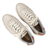 Pair of beige sneakers with white laces on a white background