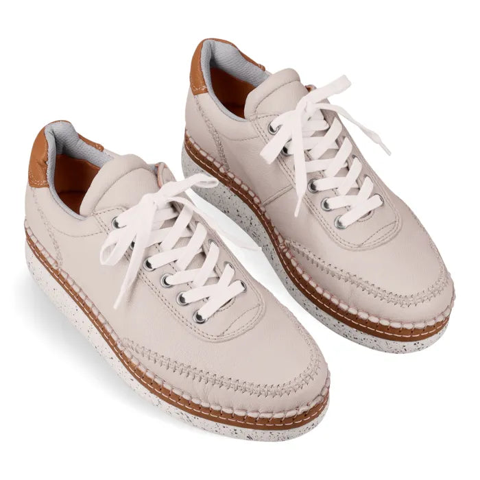 Pair of beige sneakers with white laces on a white background