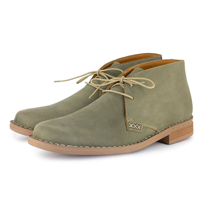 Pair of olive suede boots with brown soles on a white background