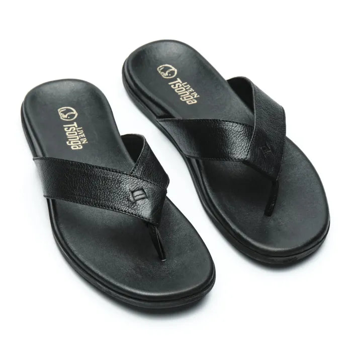 A pair of black leather thong sandals with a textured grain finish, featuring the brand name 'Tsonga' printed in gold on the footbeds, set against a plain white background.