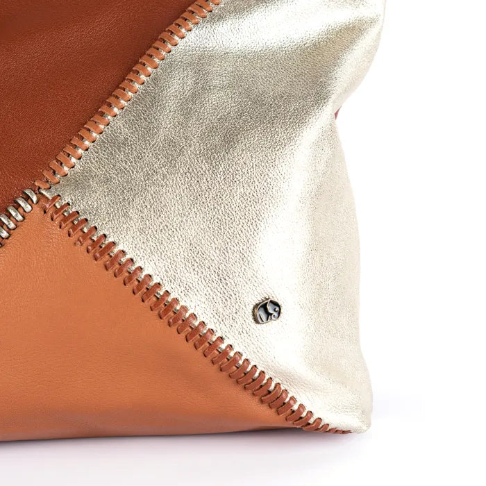 Close-up of a leather tote bag with gold and brown colours on a white background