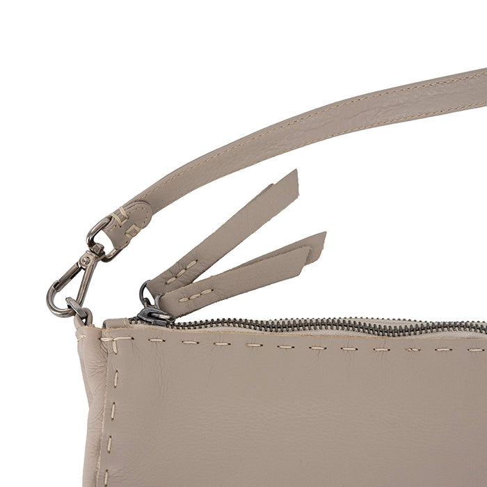 Close-up of a beige leather bag with a zipper and strap on a white background