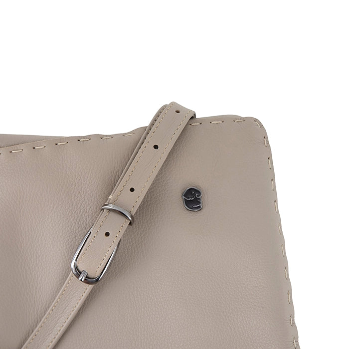 Close-up of a beige leather handbag with a strap on a white background