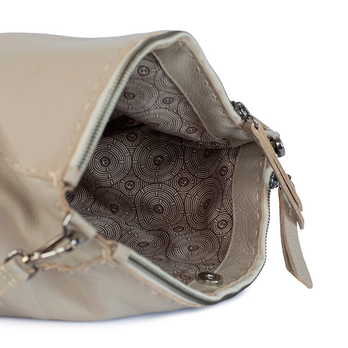 Close-up of a beige handbag with a patterned interior on a white background