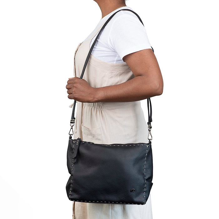 Person holding a black shoulder bag against a white background