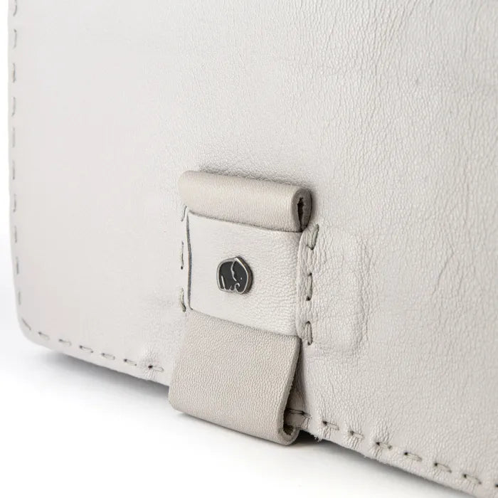 Close-up of a light grey leather bag with a brand logo on a white background