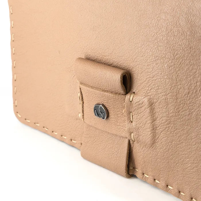 Close-up of a beige leather bag with stitching detail on a white background