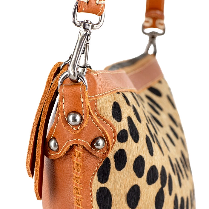 Close-up of a handbag with cheetah print and tan leather accents on a white background