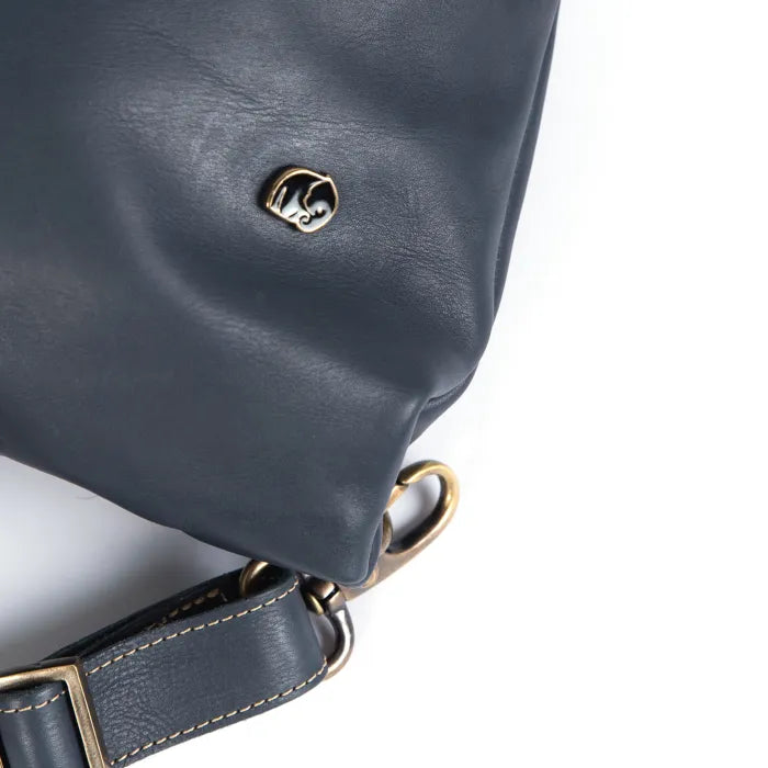 Close-up of a blue leather bag with gold hardware on a white background