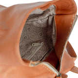 Close-up of a tan leather bag with a patterned interior pocket.