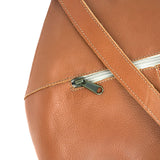 Close-up of a tan leather bag with a zipper on a white background