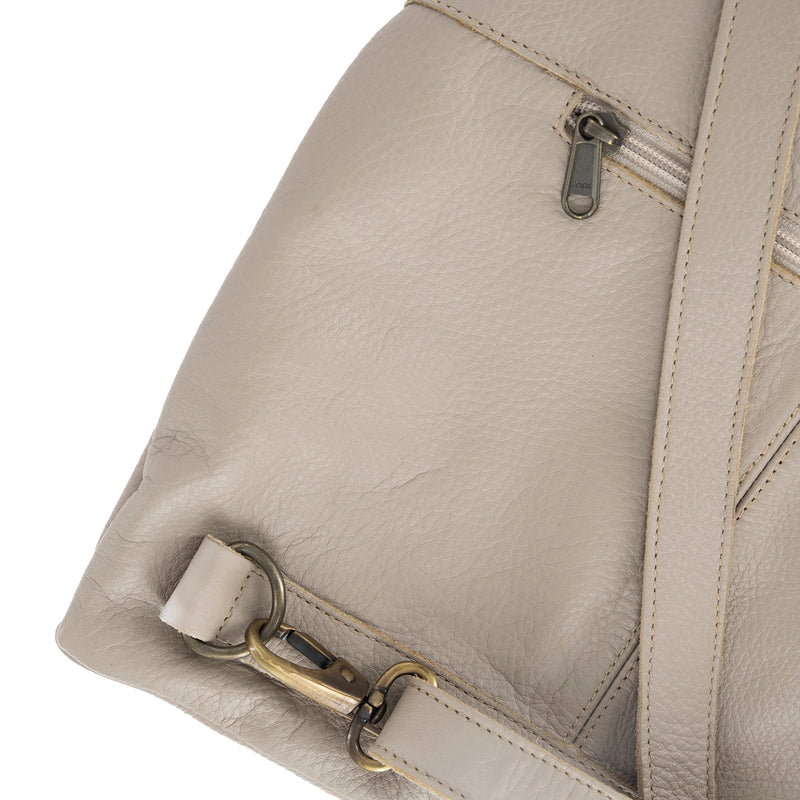 Close-up of a beige leather bag with a strap and zipper detail on a white background