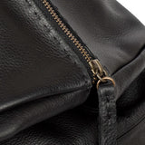 Close-up of a black leather bag with a gold zipper.