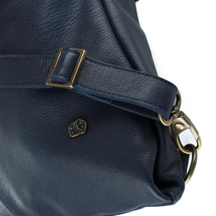 Navy blue leather handbag with brass buckle and strap on a white background