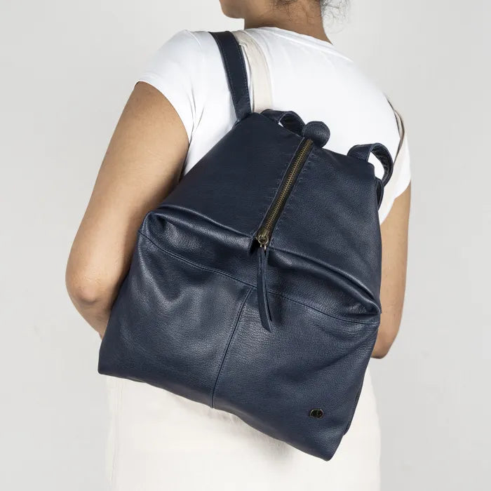 Person wearing a navy blue backpack on a plain background