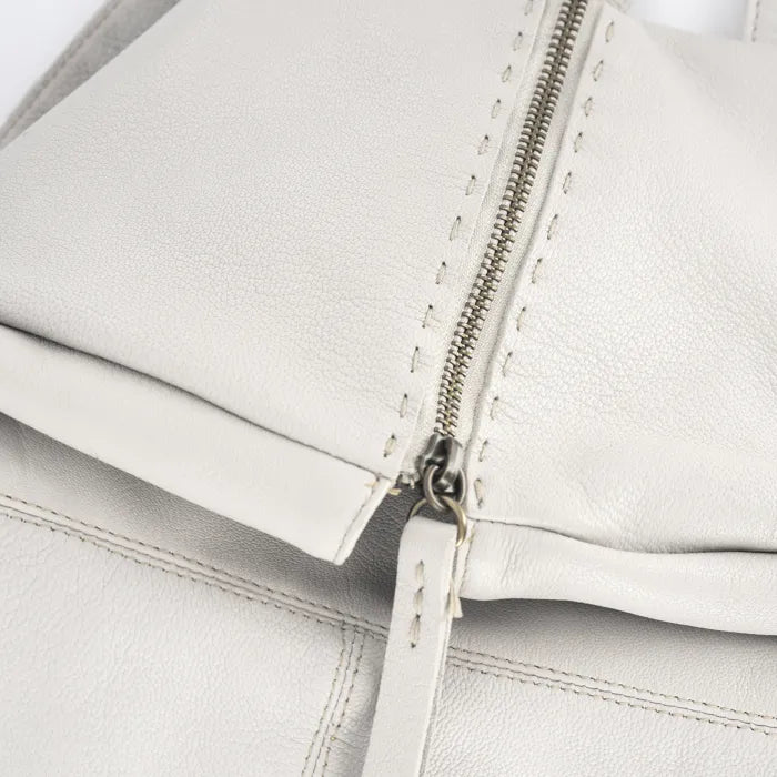 Close-up of a cream leather bag with a zipper on a light gray background