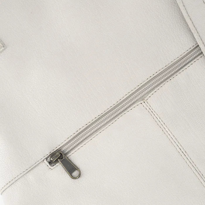 Close-up of a cream zipper on a white leather surface