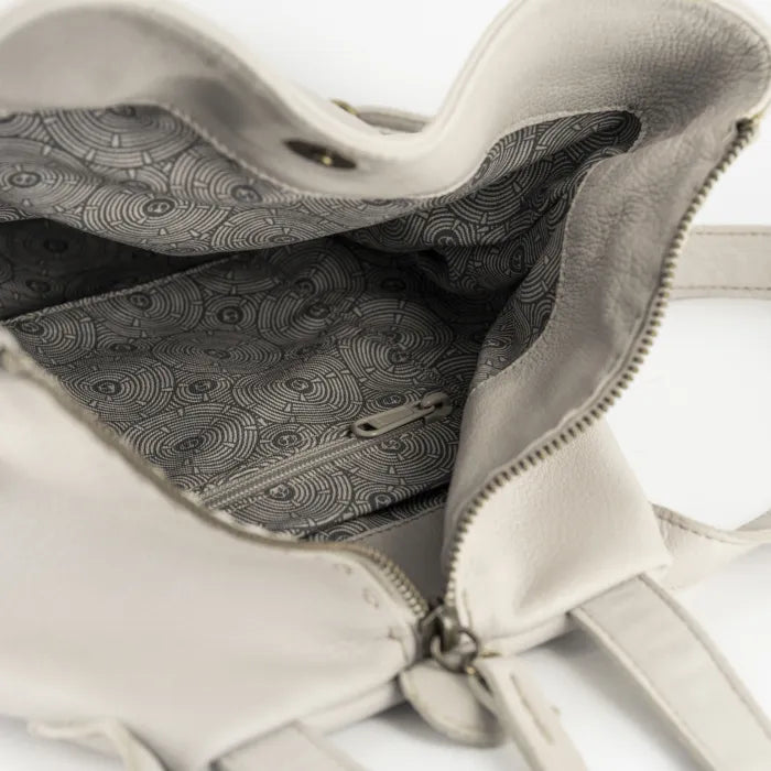 Close-up of a cream handbag with a patterned interior on a white background