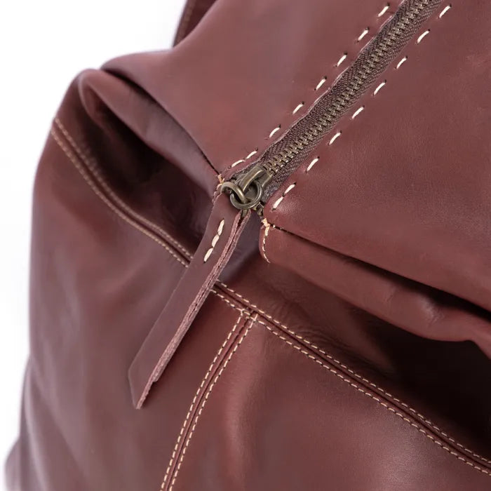 Close-up of a maroon leather bag with a zipper on a white background