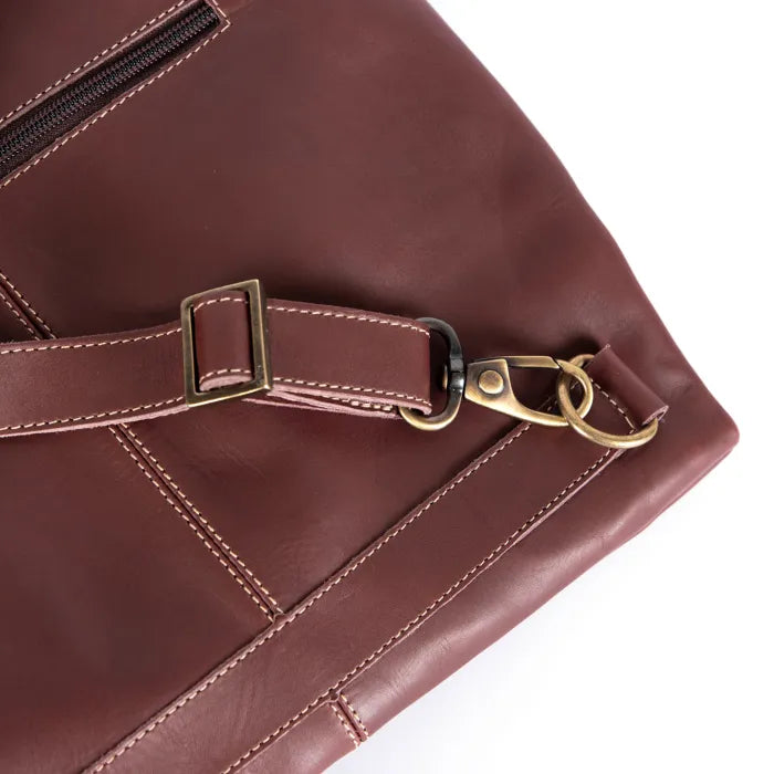 Close-up of a maroon leather bag with a gold buckle and clasp on a white background