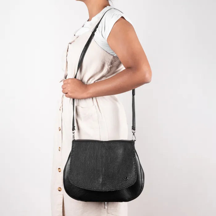 Person holding a black leather handbag against a white background