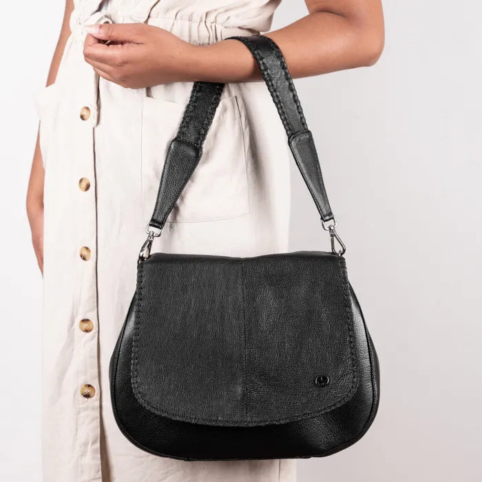 Black leather handbag held by a person  on a light gray background