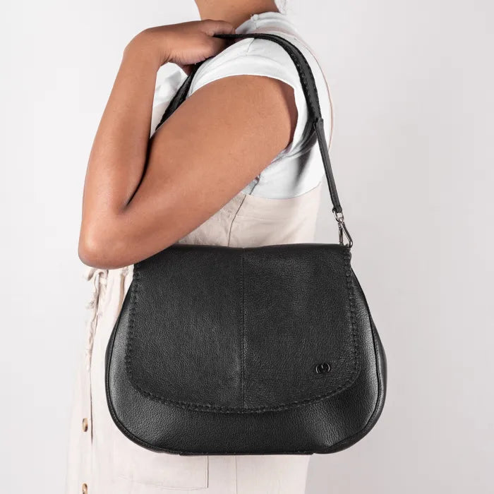 Person carrying a black handbag on a plain background