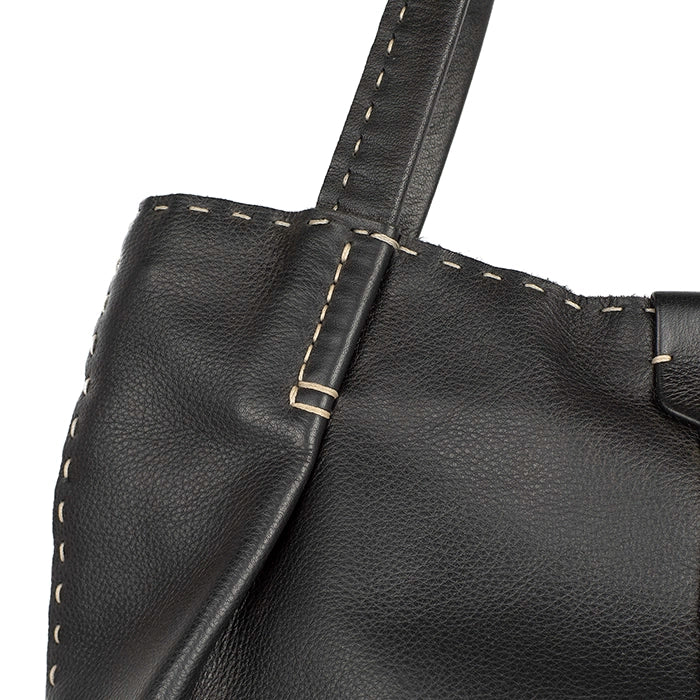 Close-up of a black leather handbag with visible stitching on a white background
