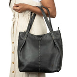 Black leather handbag held by a person on a white background