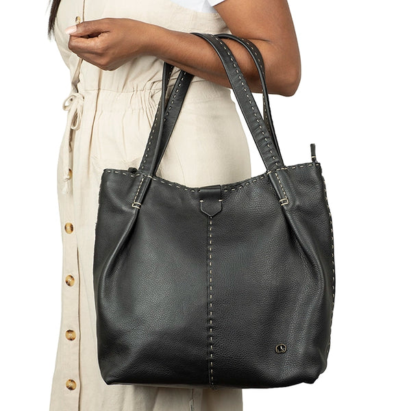 Black leather handbag held by a person on a white background