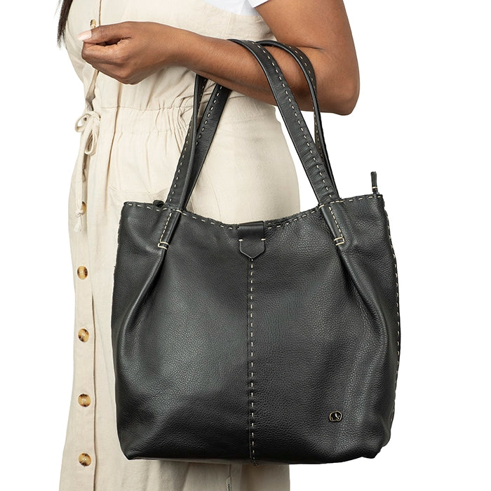 Black leather handbag held by a person on a white background