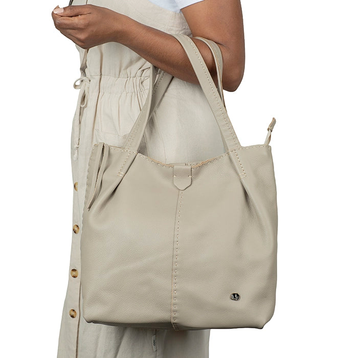 Beige tote bag held by a person on a white background