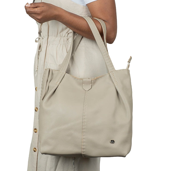 Beige tote bag held by a person on a white background
