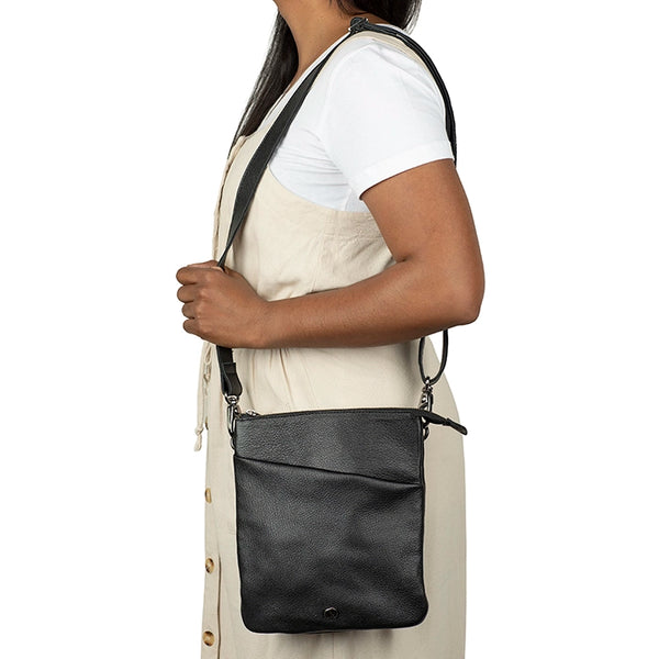Person wearing a black crossbody bag on a white background