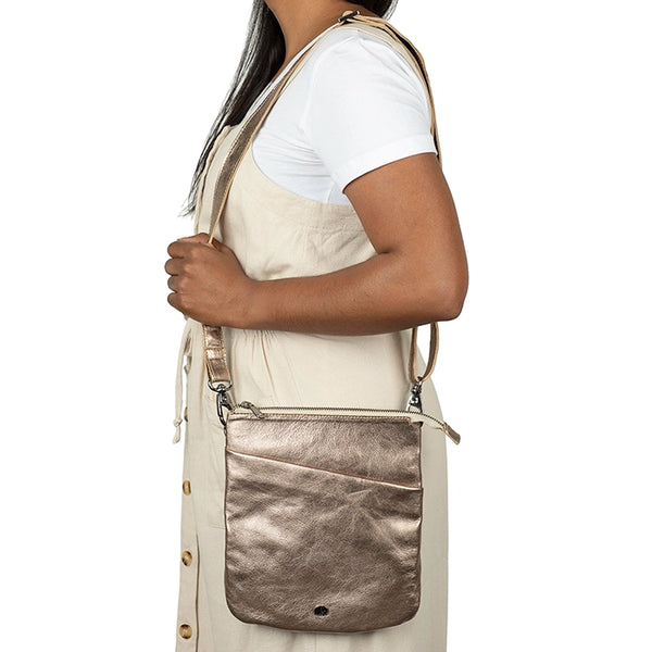 Person carrying a metallic cross body bag on a white background