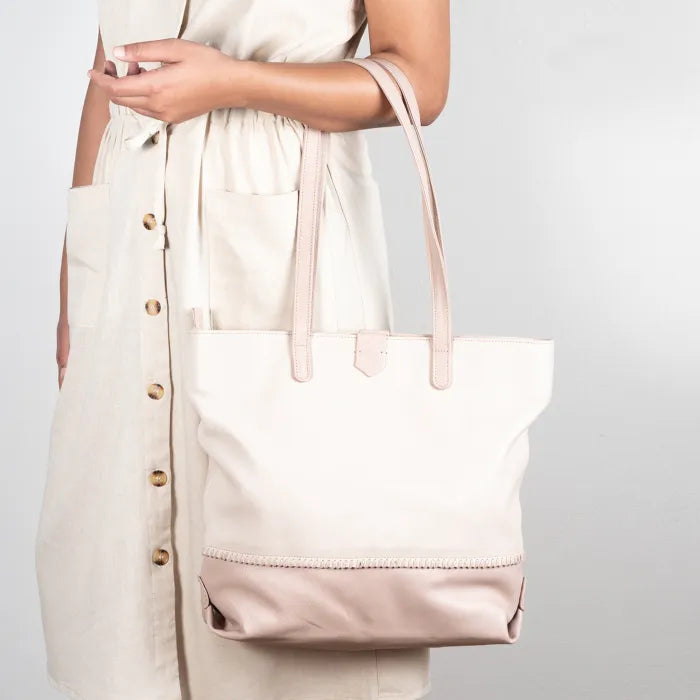 Person holding a cream and pink tote bag against a plain background