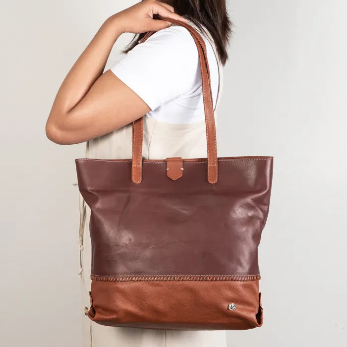 Maroon and Brown leather tote bag held by a person on a plain background