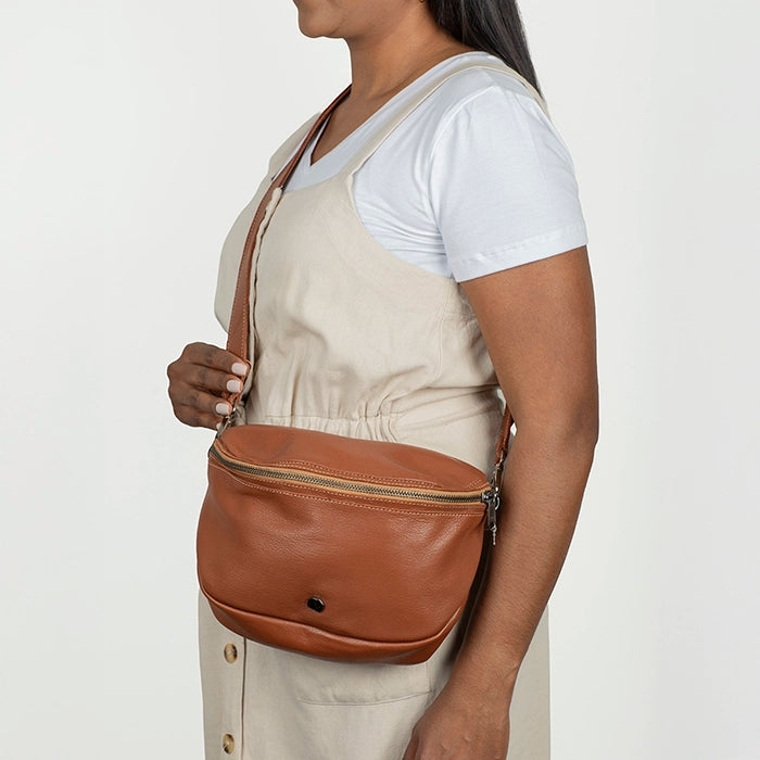 Person wearing a brown leather cross body bag.