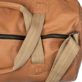 Close-up of a tan leather bag with beige straps on a white background