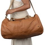 Tan leather handbag being carried by a person.