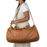 Person carrying a tan leather bag on a white background