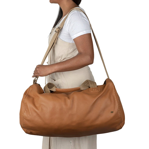 Person carrying a tan leather bag on a white background