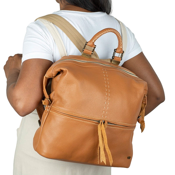 Person wearing a tan leather backpack on a white background